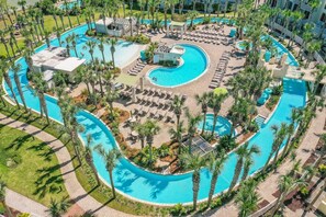Vue aérienne d’un complexe hôtelier doté de plusieurs piscines, de chaises longues et de palmiers.