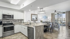 A modern kitchen with white cabinetry, a built-in microwave, stainless steel appliances, and a marble countertop island. - SANDPIPER PH02- 3BR PENTHOUSE @ DESTIN WEST-WHAT A VIEW!! (Fort Walton Beach)