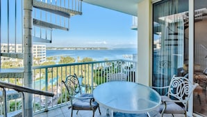 A balcony with a glass table and chairs, overlooking a pool and buildings. - SANDPIPER PH02- 3BR PENTHOUSE @ DESTIN WEST-WHAT A VIEW!! (Fort Walton Beach)