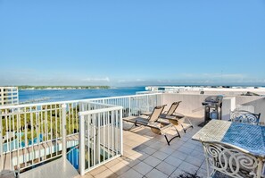 Enjoy breathtaking ocean views from this rooftop terrace, featuring a table, chairs, and grill area.