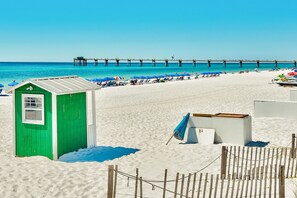 Relax on the beach with a lifeguard station nearby, surrounded by lounge chairs and umbrellas.