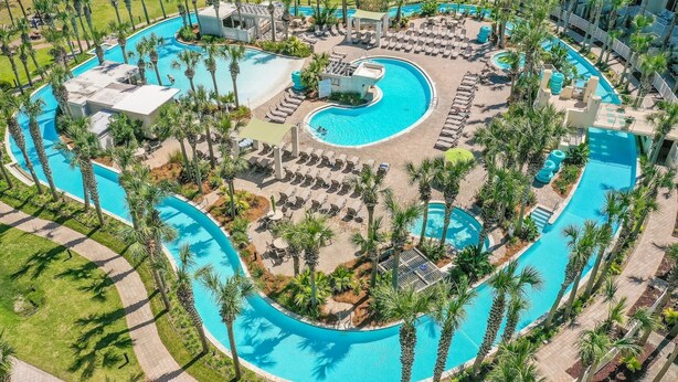 An aerial view of a resort with multiple swimming pools, sun loungers, and palm trees. - SANDPIPER PH02- 3BR PENTHOUSE @ DESTIN WEST-WHAT A VIEW!! (Fort Walton Beach)
