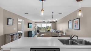 A modern kitchen with a central island, stainless steel sink, and overhead lighting.