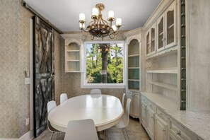 A dining room with a round table, white chairs, a chandelier, and a view of trees through a window. - BUNGALOWS @ SEAGROVE! Near the Beach!!  Community Pool!! (Santa Rosa Beach)