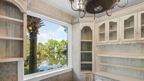 A room with a large window overlooking a lake, a dining area with a round table, and built-in wooden shelves. - BUNGALOWS @ SEAGROVE! Near the Beach!!  Community Pool!! (Santa Rosa Beach)