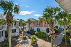 A courtyard with palm trees, a pathway, and buildings with balconies. - BUNGALOWS @ SEAGROVE! Near the Beach!!  Community Pool!! (Santa Rosa Beach)