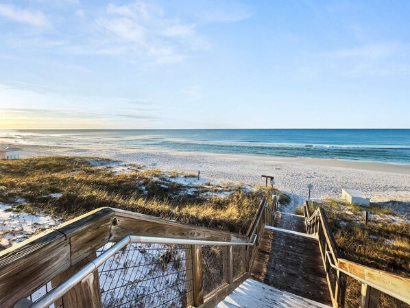 Eine Holztreppe führt zu einem Strand mit freiem Blick auf den Ozean.