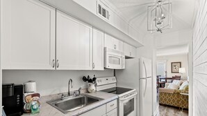 A kitchen with white cabinets, a microwave, stove, sink, and a coffee maker. - Newly renovated, 3rd floor, ocean view condo + Free Attraction Tickets! (North Myrtle Beach)