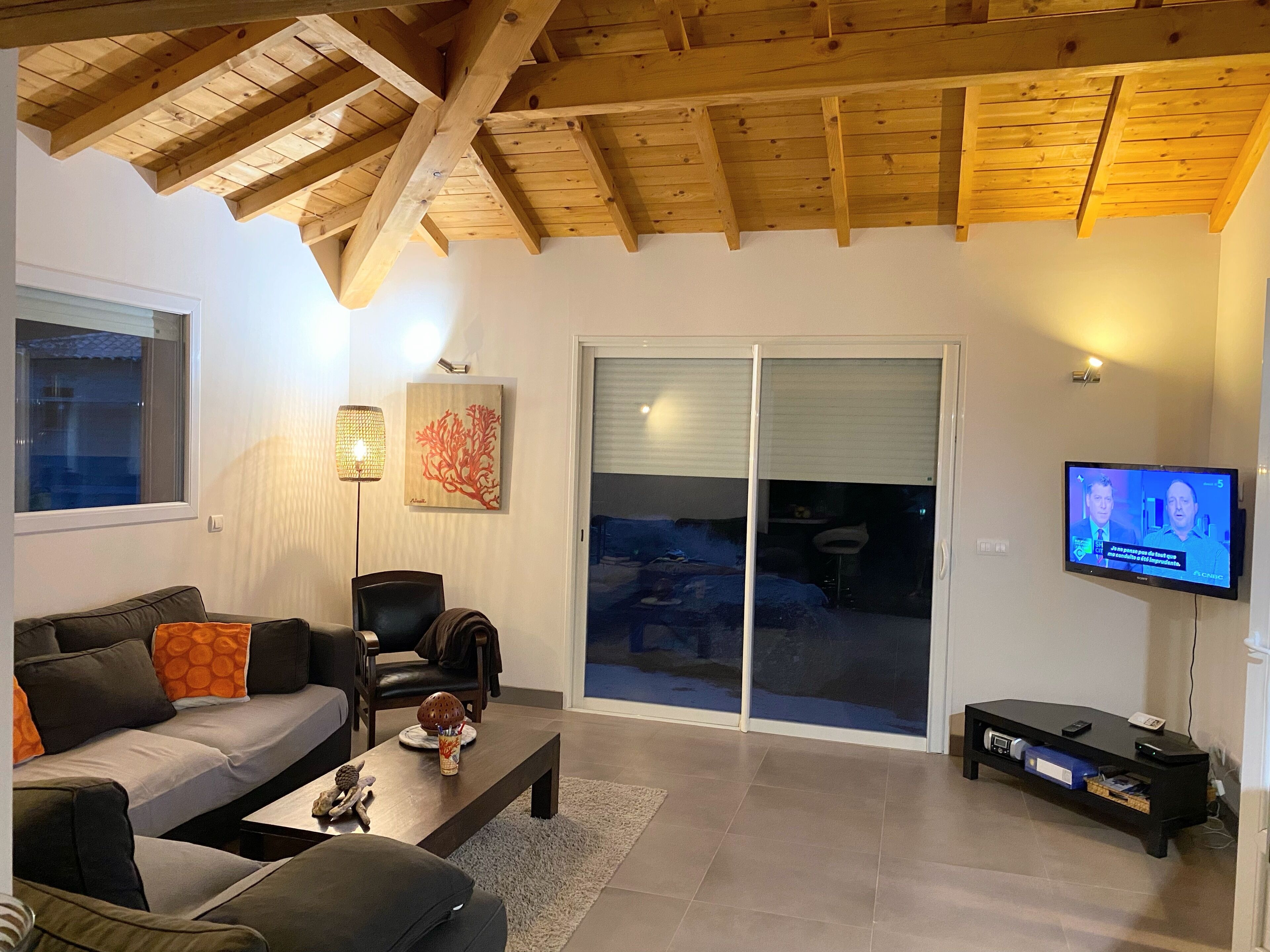 Un soggiorno con un divano, un tavolino, una televisione e una porta scorrevole in vetro.
