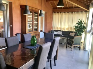 Ein Essbereich mit Holztisch und -stühlen, einer grünen Vase und einer Couch im Hintergrund.