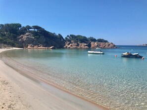 A clear beach with calm waters, boats, and rocky cliffs. - Villa 4ch: An Idyllic Haven of Peace (Figari)