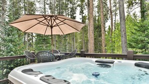 A hot tub on a deck with an umbrella, surrounded by trees. - Retreat at Shock Hill Home: Walk to Gondola (Breckenridge)