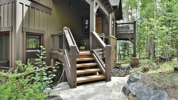 A wooden staircase leading to a porch with a stone wall and a wooden door. - Retreat at Shock Hill Home: Walk to Gondola (Breckenridge)