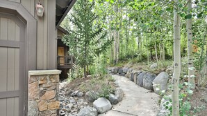 A stone pathway leading to a wooden door, surrounded by rocks and trees. - Retreat at Shock Hill Home: Walk to Gondola (Breckenridge)