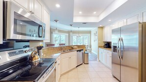 A modern kitchen with stainless steel appliances, a granite countertop, and white cabinetry.