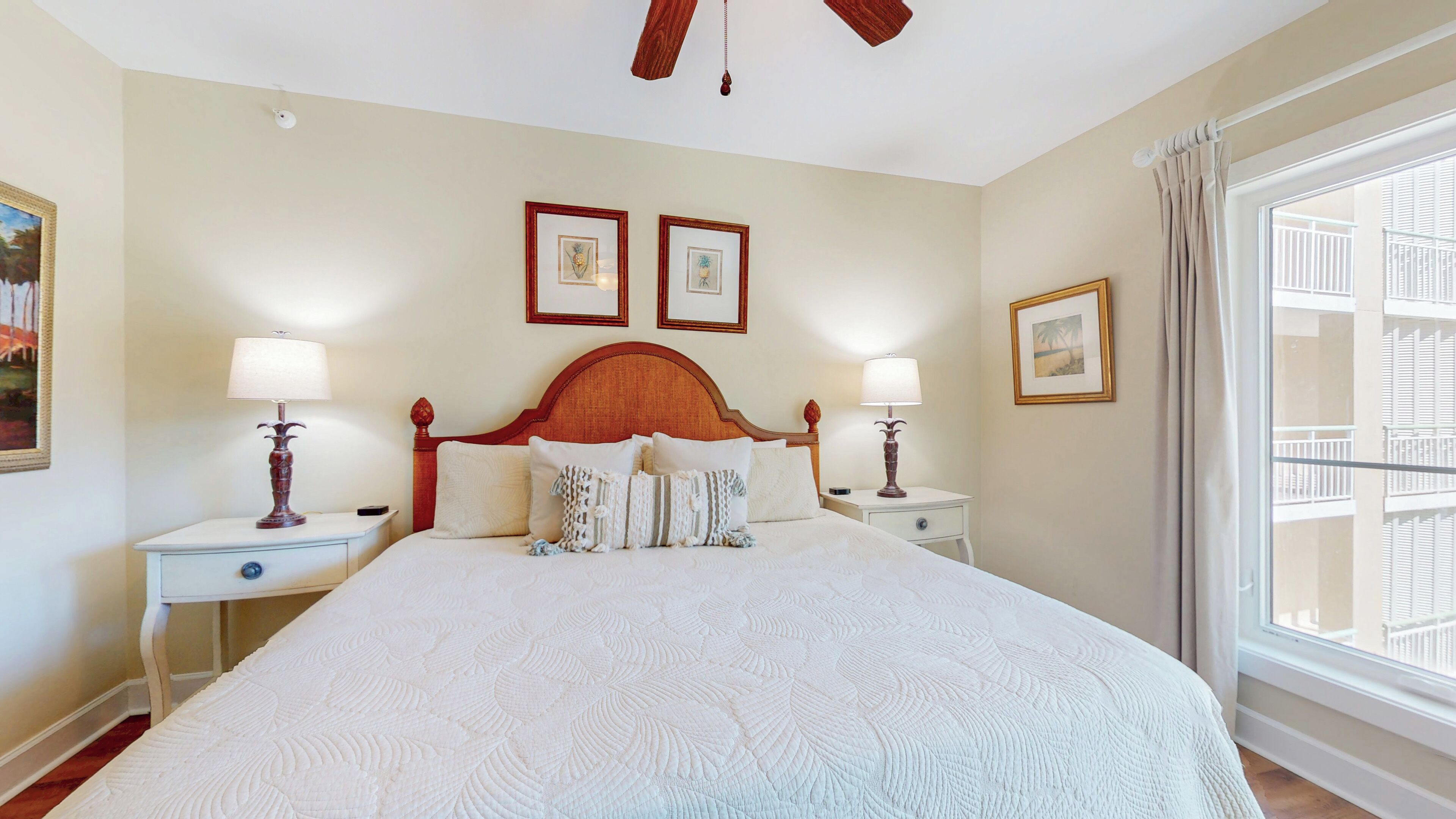 A large bed with a wooden headboard, two bedside tables with lamps, and framed pictures on the walls.