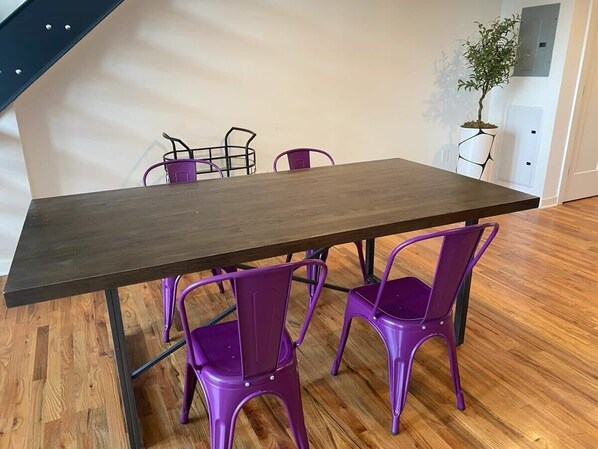 Ein Esstisch mit vier violetten Stühlen, einem Blumentopf und einer Treppe im Hintergrund.