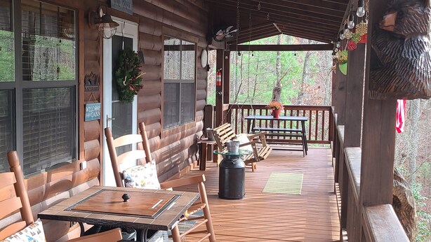 A wooden cabin with a porch, furnished with wooden chairs and a table. - "  Lazy Bears Cabin" Located in Cherry Log
Highly Rated  overall by Guest (Blue Ridge)