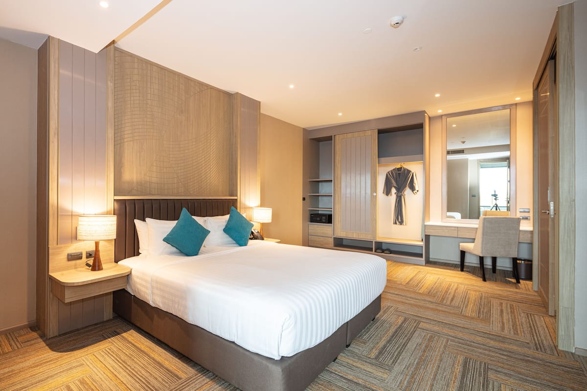 Habitación de hotel con una cama grande, un escritorio, un armario y un espejo.