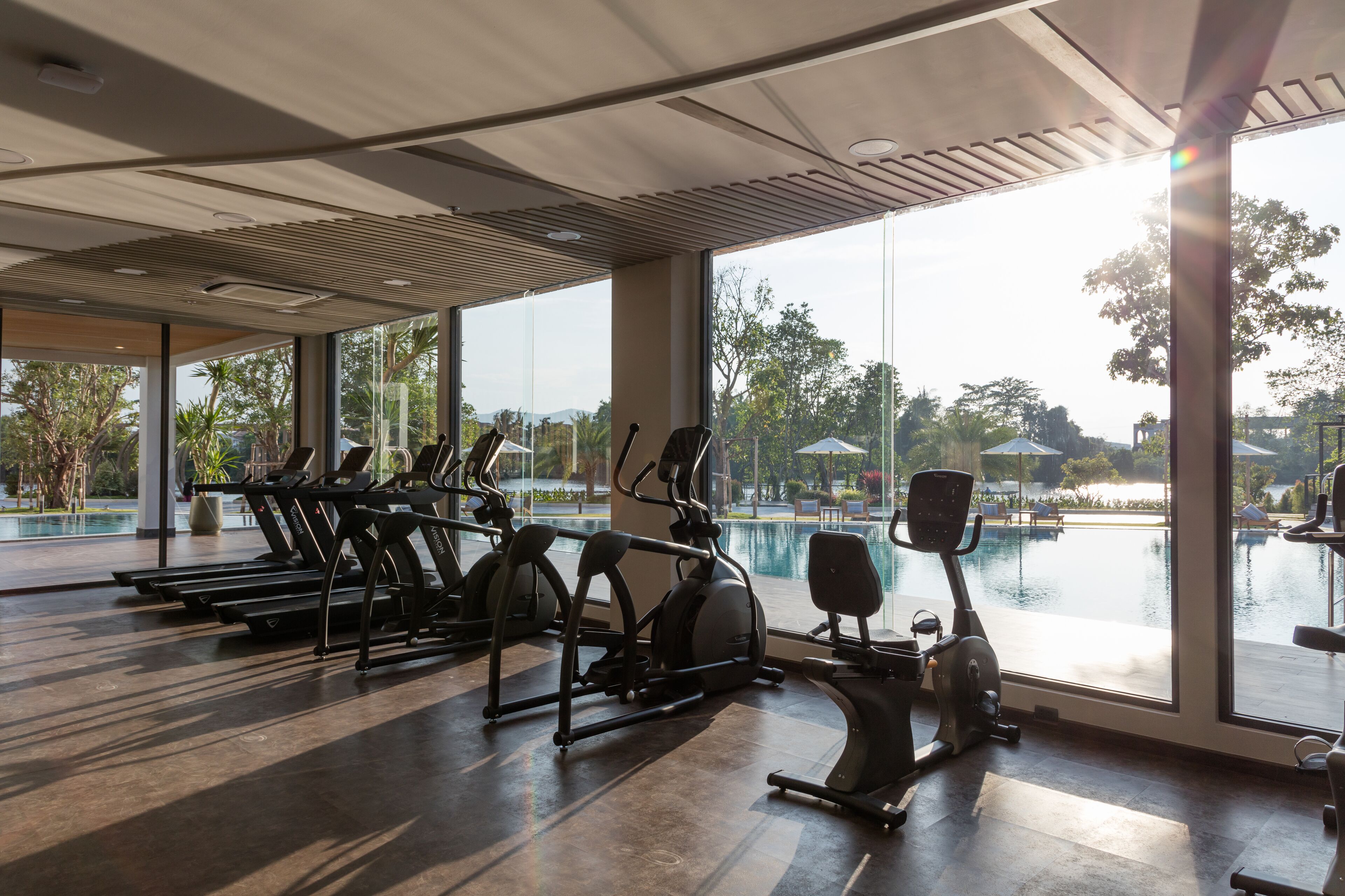 Une salle de sport équipée de matériel d’exercice et offrant une vue sur une piscine.