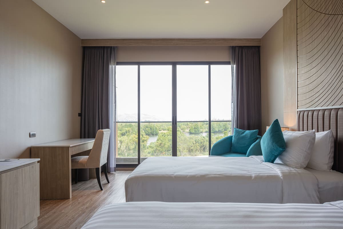 Habitación de hotel con una cama grande, un escritorio y vistas a un paisaje verde por la ventana.
