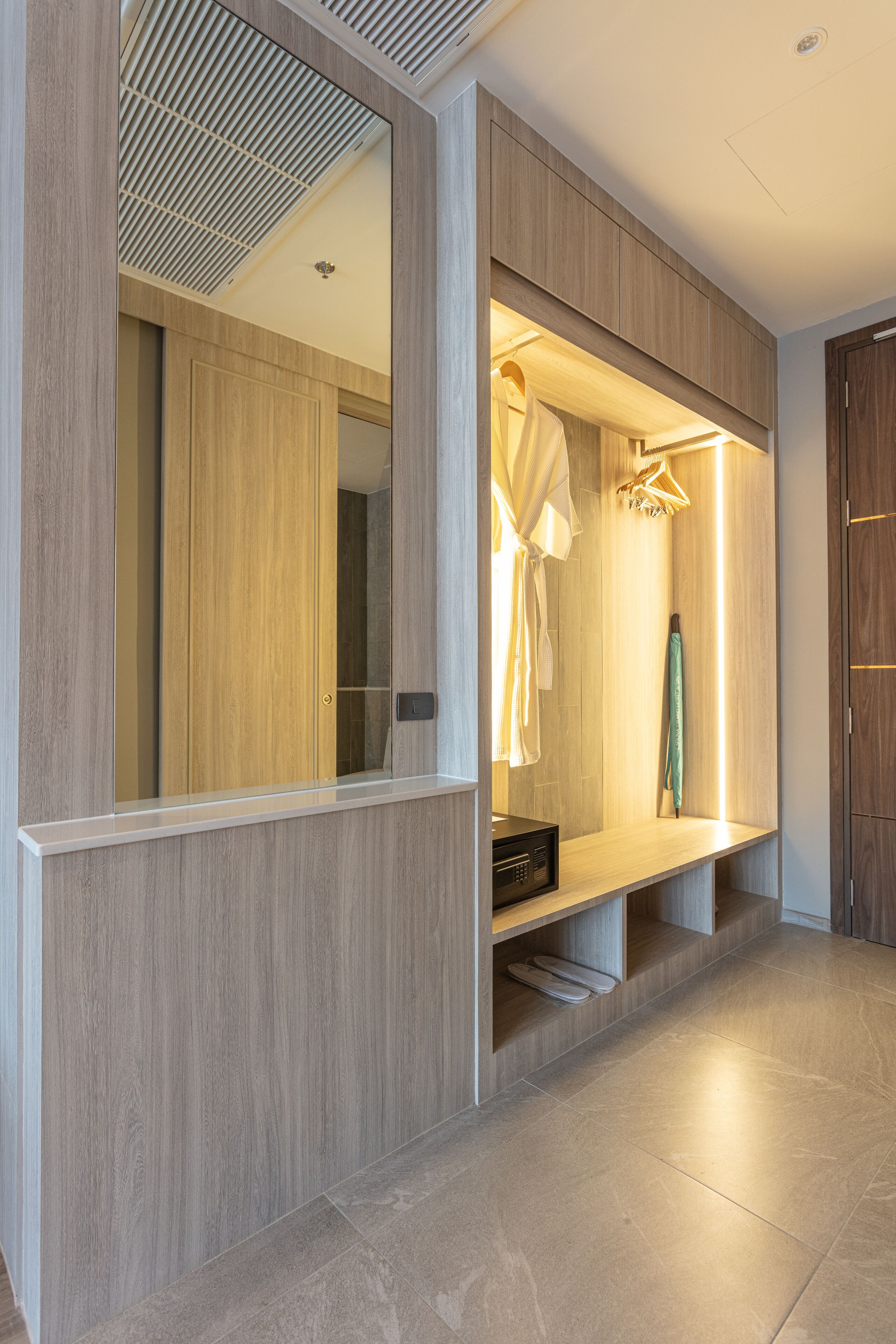 A modern bathroom with a wooden vanity, a mirror, and a towel rack.