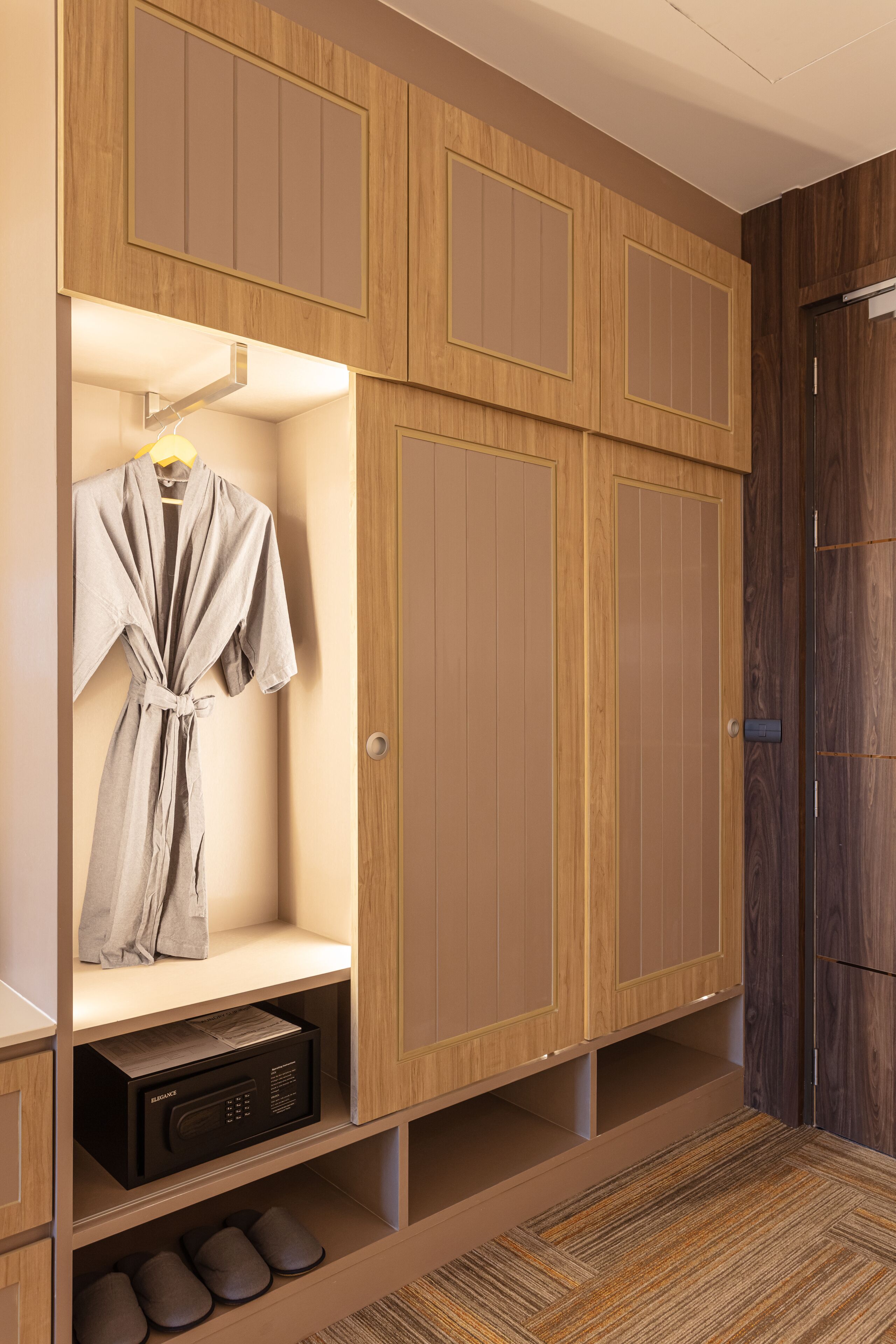 A walk-in closet with wooden paneling, a robe hanging on a rack, and a shoe rack with multiple pairs of shoes.