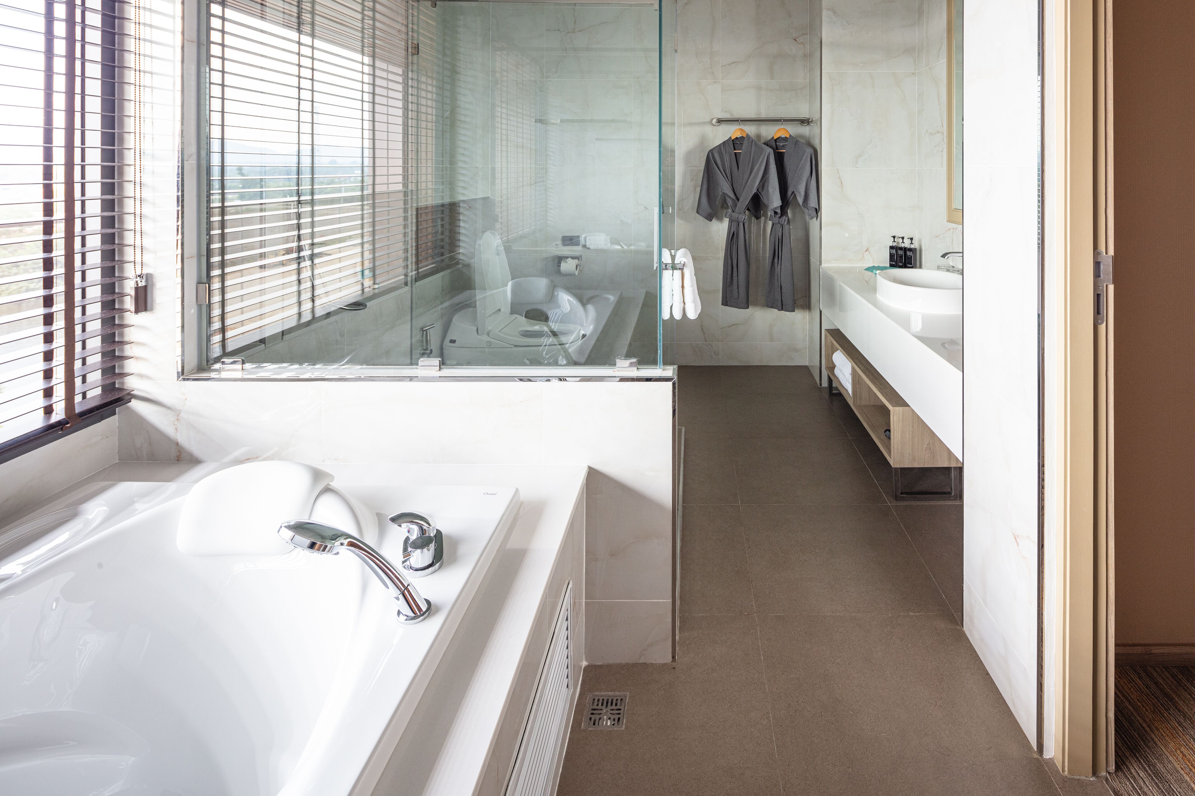 A modern bathroom with a glass-enclosed shower, a large bathtub, and a vanity with a mirror.