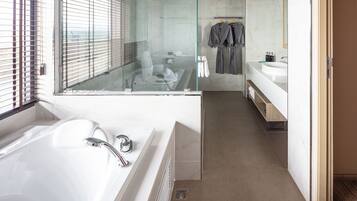 A modern bathroom with a glass-enclosed shower, a large bathtub, and a vanity with a mirror.