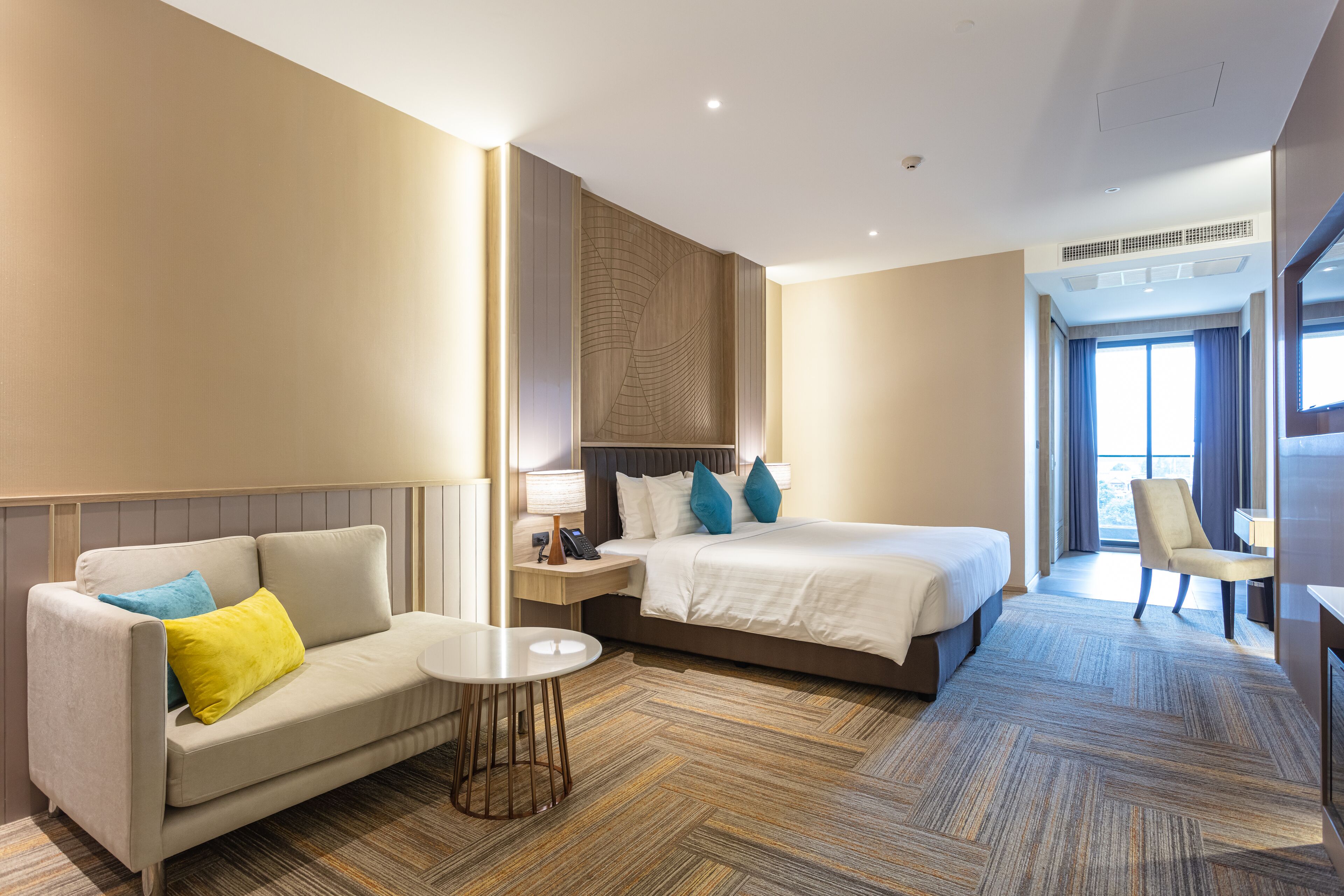 A hotel room with a bed, a sofa, a small table, and a chair.