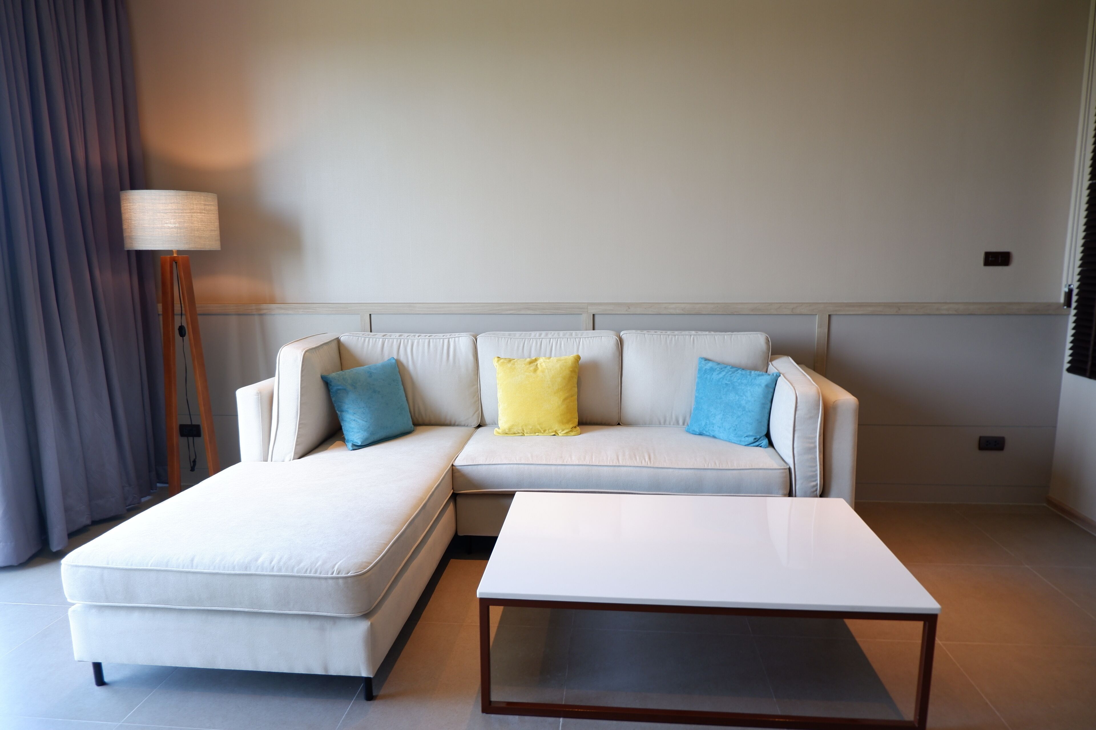 A modern living room with a sectional sofa, a coffee table, and a floor lamp.