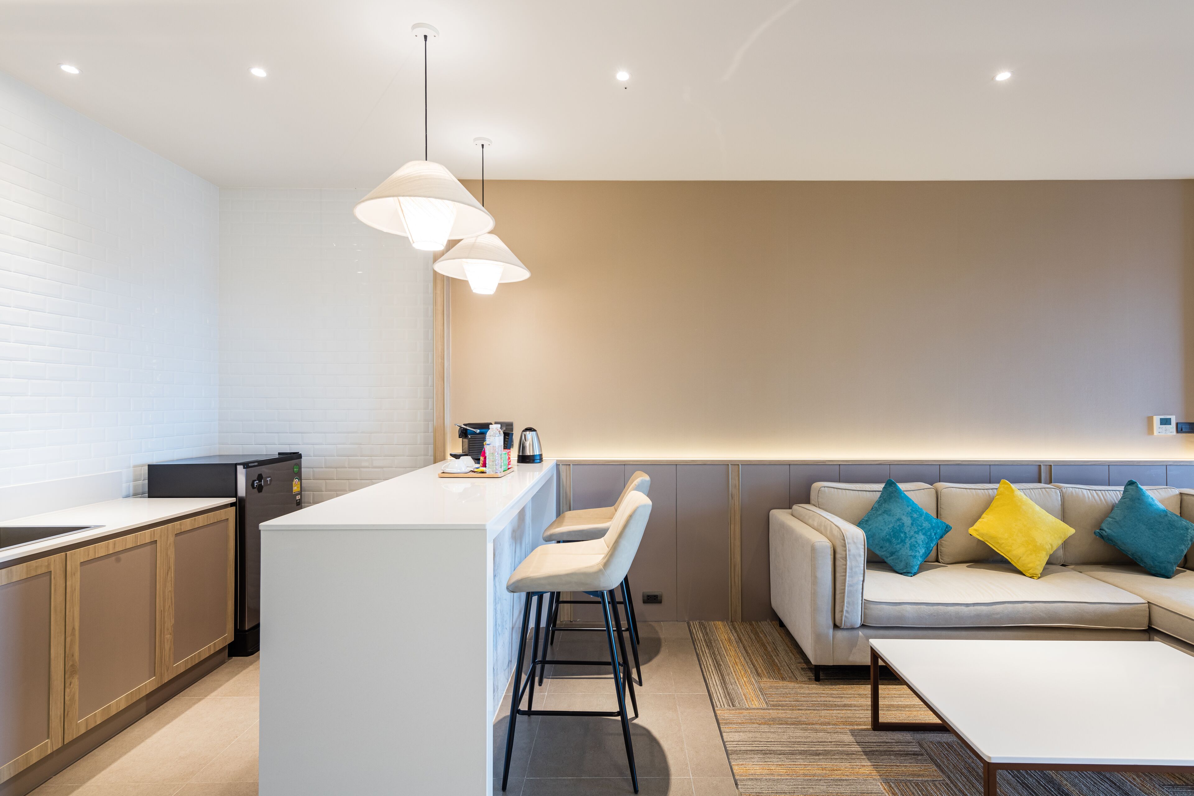 A modern kitchen with a white island, bar stools, and a built-in oven.