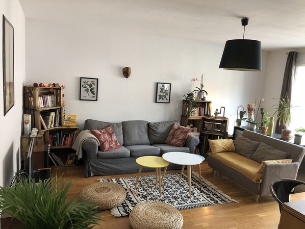 Una sala de estar con un sofá gris, una mesa amarilla y una alfombra estampada.