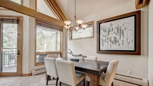 A dining area with a dark wooden table, beige upholstered chairs, a chandelier, and a large abstract painting on the wall. - Luxury 4 Bed Pines Townhome Amongst The Peace And Quiet 4 Bedroom Townhouse by RedAwning (Avon)