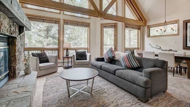 A spacious living room with a fireplace, large windows, and a high ceiling with exposed beams. - Luxury 4 Bed Pines Townhome Amongst The Peace And Quiet 4 Bedroom Townhouse by RedAwning (Avon)