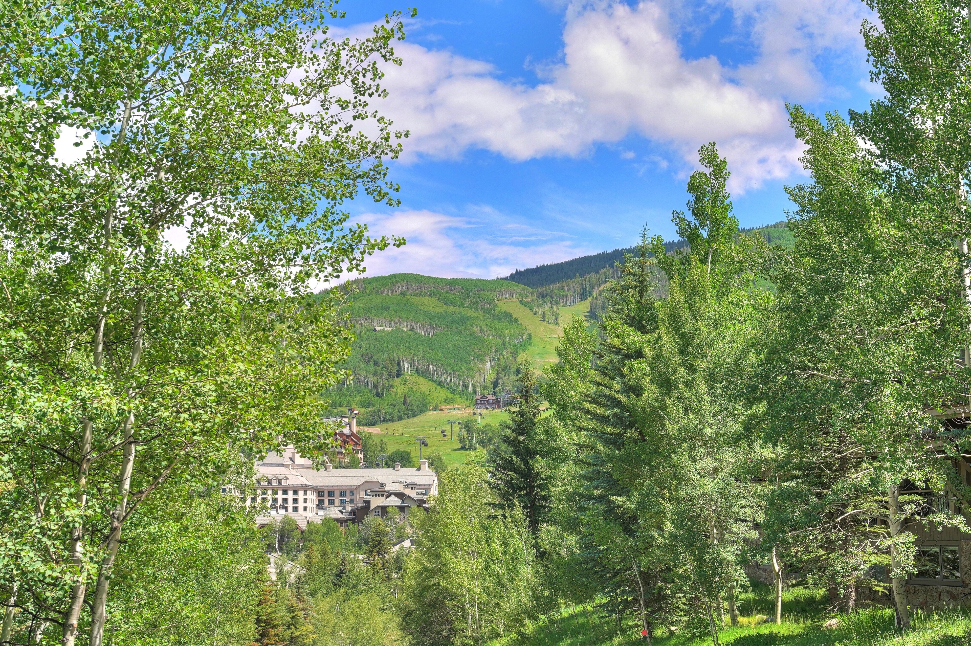 A large building surrounded by lush green trees and hills.