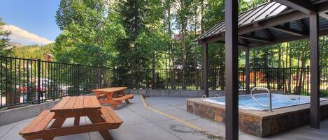 An outdoor patio area with picnic tables and a hot tub.