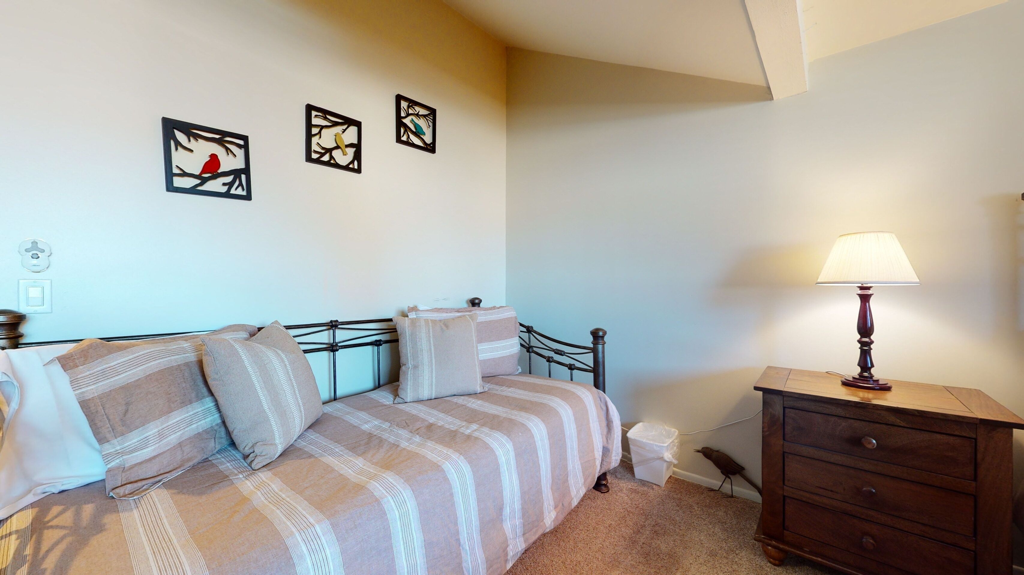 A bedroom with a bed, a nightstand, a lamp, and wall art.