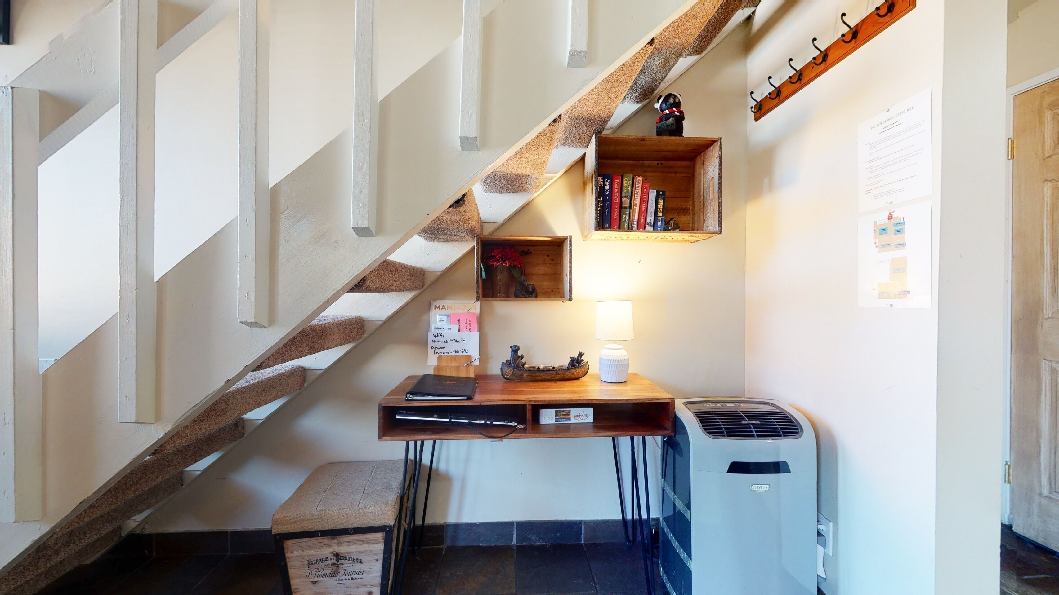 Una escalera con detalles de madera, un escritorio con una lámpara, un radiador y un estante pequeño con libros y un objeto decorativo.