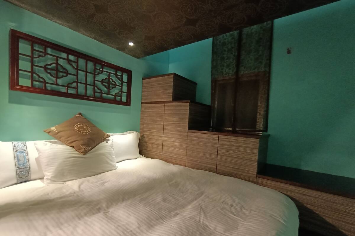 A bedroom with a bed, a wooden cabinet, and a decorative wall piece.