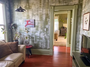 Un salon avec un canapé, un ventilateur, un tableau et un téléviseur.