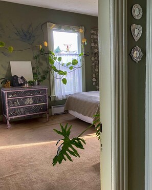 Une chambre à coucher avec un lit, une commode et une fenêtre avec des rideaux.