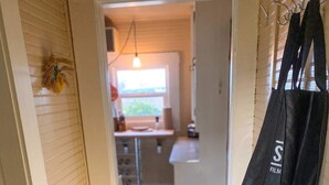 Un pasillo con una puerta, una mesa de vidrio con revistas y un bolso negro colgado en la pared.