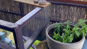 Un balcón con un cerado tejido, una planta en maceta y un pequeño comedero para pájaros.