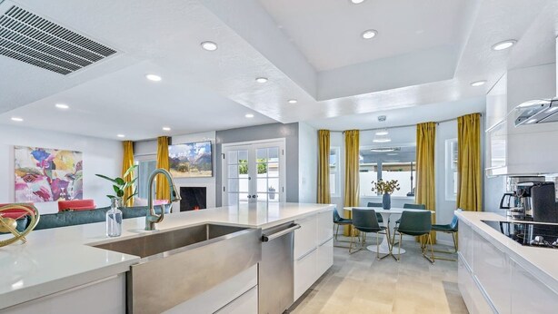 A modern kitchen with a central island, built-in appliances, and a dining area with yellow curtains. - Modern Retreat Minutes from Shopping Dining & Golf (Scottsdale)