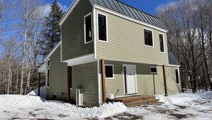 A two-story house with a gabled roof, a front porch, and a snow-covered yard. - Perfect house surrounded by National Forest to get away and decompress!!! (Winhall)