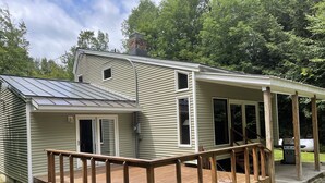 A two-story house with a deck, a covered porch, and a chimney. - Perfect house surrounded by National Forest to get away and decompress!!! (Winhall)