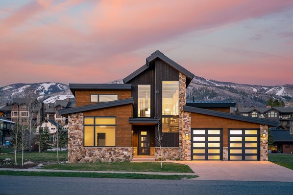 A modern two-story house with a stone facade, large windows, and a garage.
