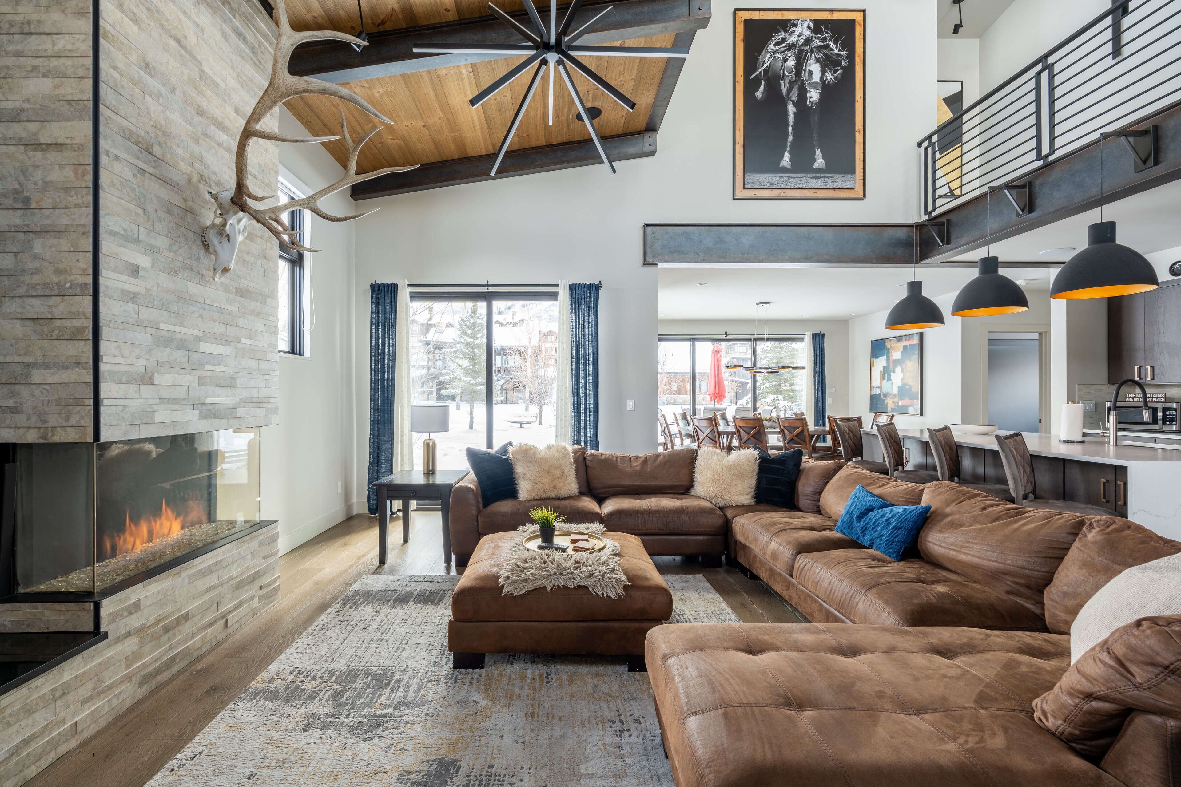 A spacious living room with a large sectional sofa, a fireplace, and a modern ceiling design.