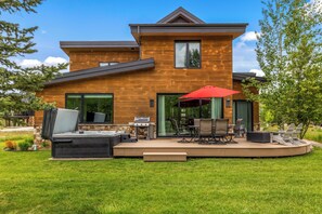 Una casa moderna con patio, mobili da esterno e barbecue.